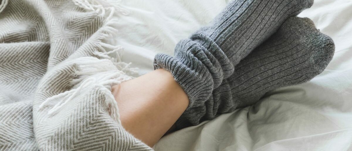 Nahaufnahme von Füßen mit kuscheligen grauen Socken.