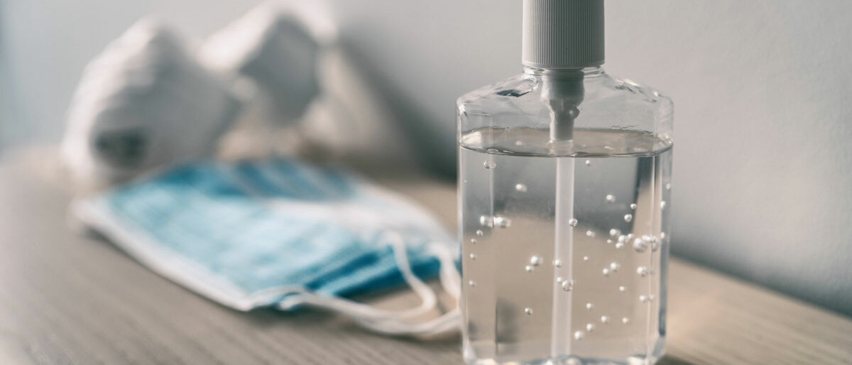 Vergiftung Ein Desinfektionsspender für die Hände, im Hintergrund Mund-Nasen-Masken