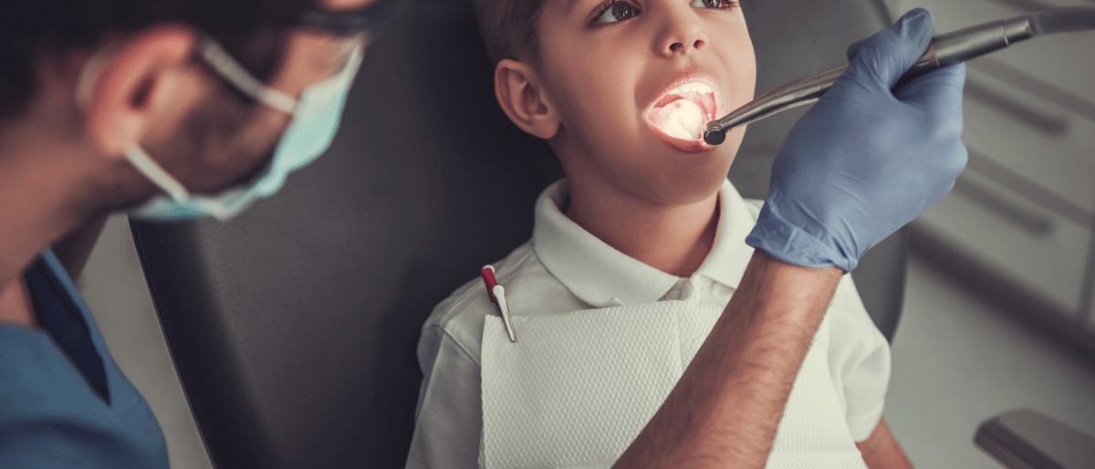 Ein Kind liegt auf der Untersuchungsliege beim Zahnarzt zur Kontrolle