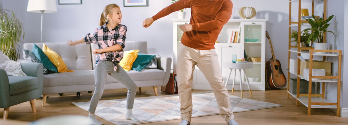 Ein Vater und seine Tochter tanzen den Floss Dance im Wohnzimmer.