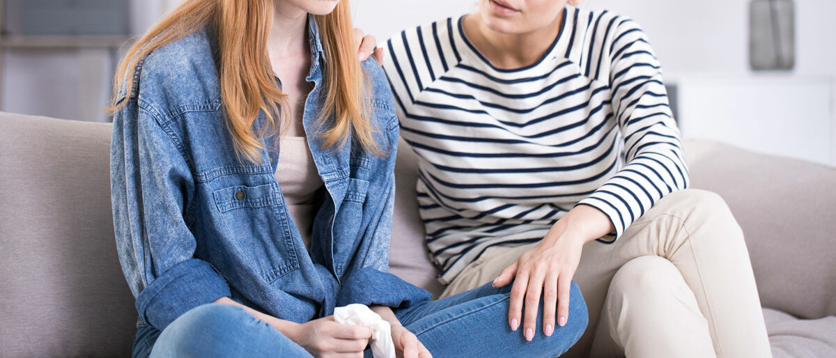 Eine junge Frau lässt sich von ihrer Mutter trösten.