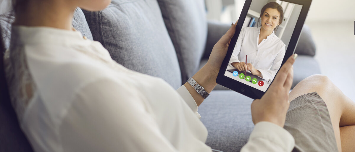 Eine Frau führt mit ihrem Tablet ein Gespräch via Videochat mit ihrer Ärztin.