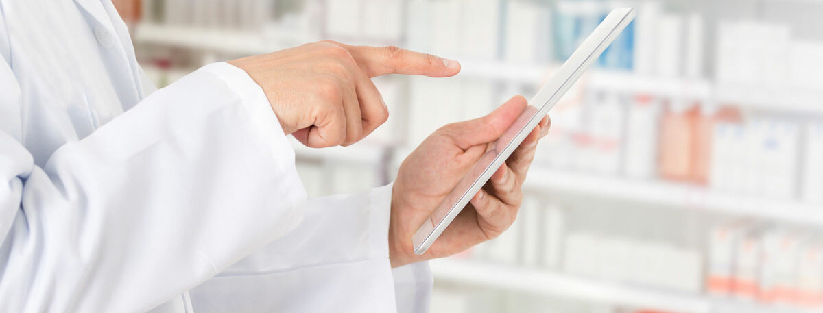 eine Person im weißen Kittel tippt auf ein Tablet