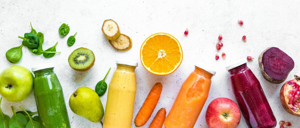 Verschiedene Smoothies und Früchte auf hellem Untergrund.