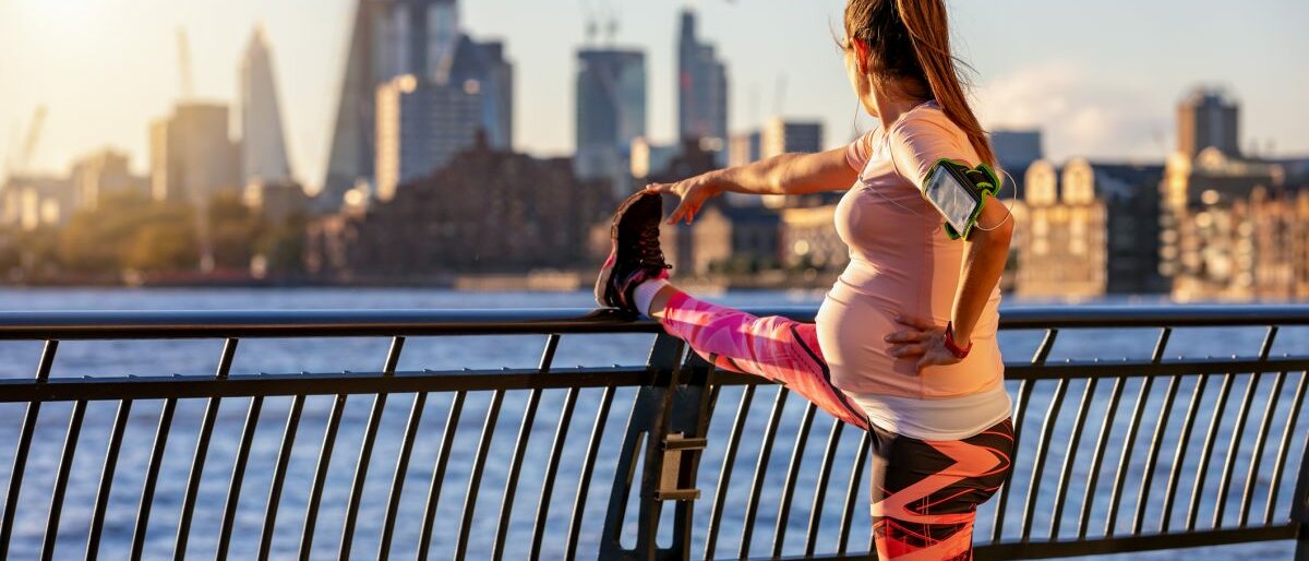 Dehnen Eine Schwangere Frau, die sich an einer Brücke dehnt.