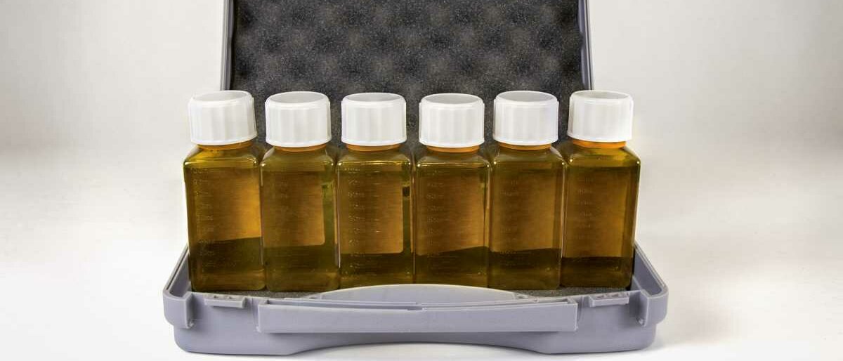 Sechs Kunststoffflaschen stehen nebeneinander in einem Koffer als Take-Home-Bezug.