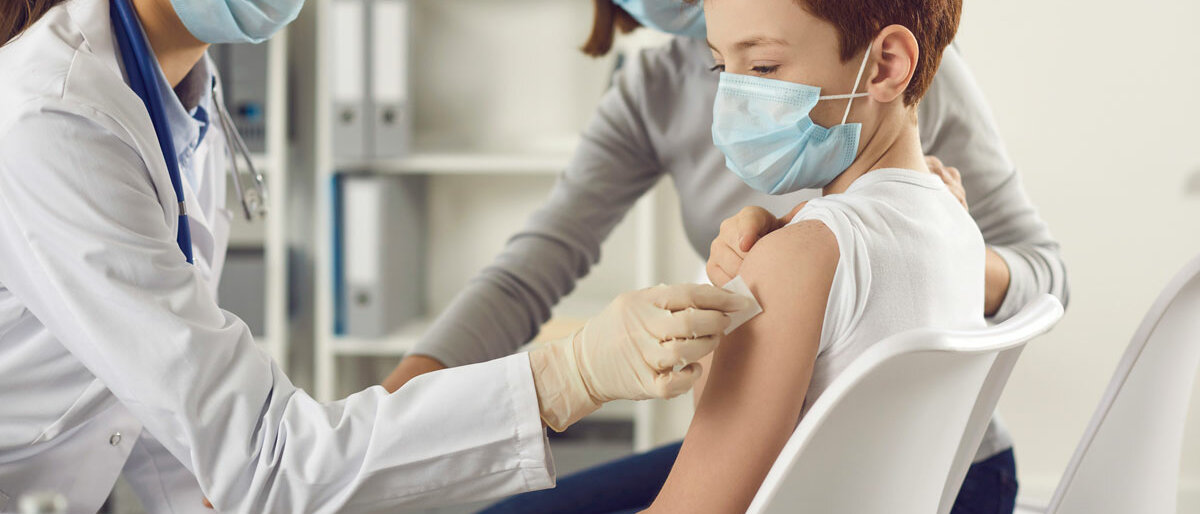 Eine Ärztin impft einen Jungen in den Oberarm.