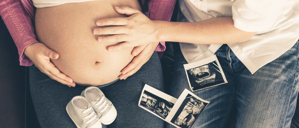 Eine schwangere Frau hält ihren Bauch.