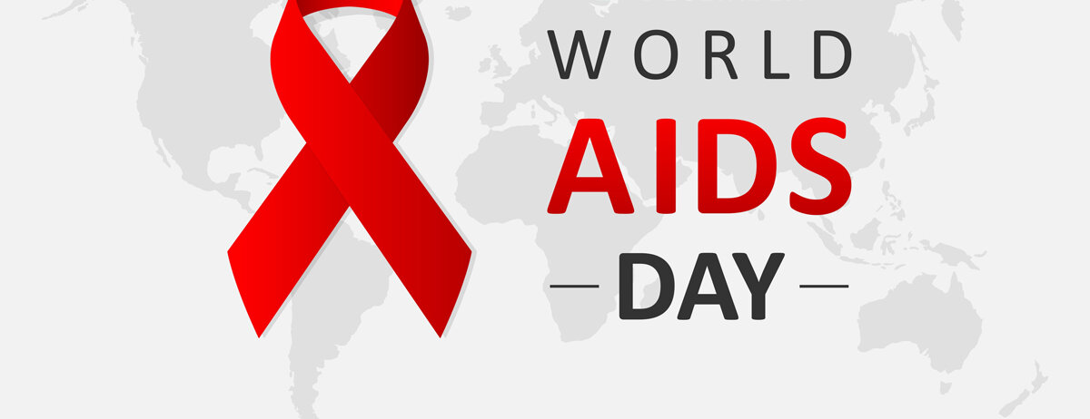 Vor einer Weltkarte ist die rote Aids-Schleife dargestellt. Ein Schriftzug sagt "1st December World Aids Day".