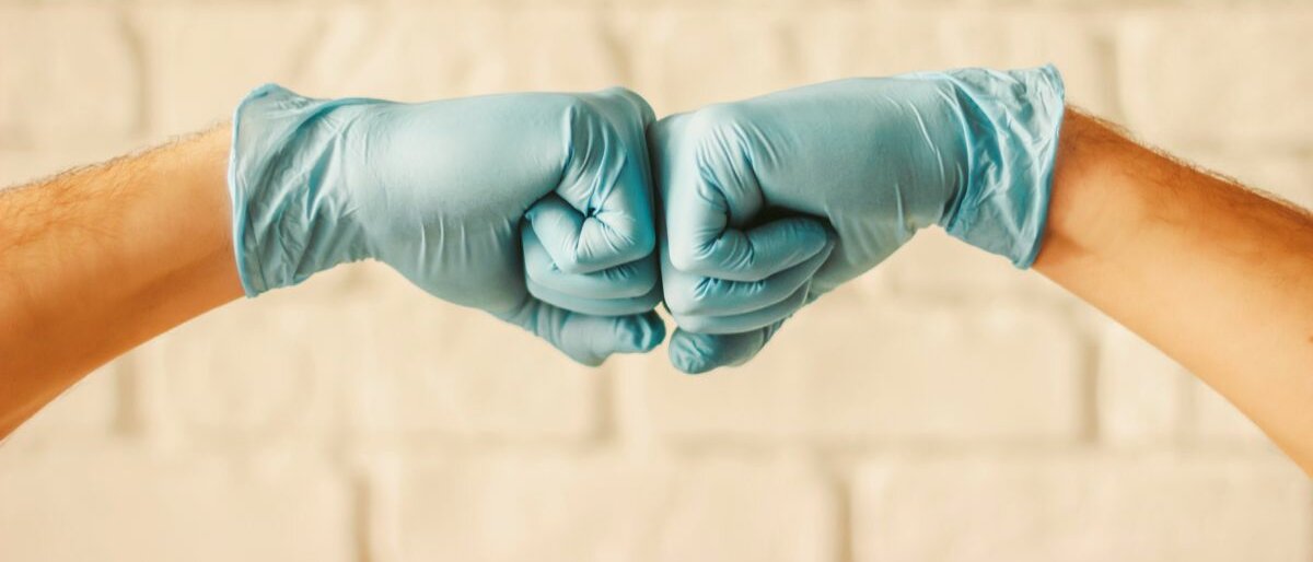 Kooperation Männer stoßen mit Schutzhandschuhen ihre Fäuste gegeneinander.