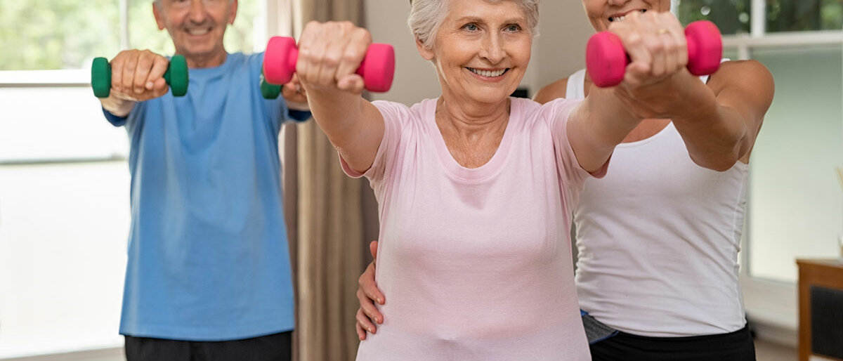 zwei Senioren bei der Gymnastik, eine Trainerin betreut sie