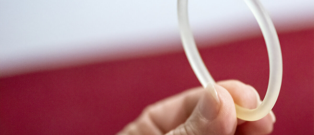 Eine Frauenhand hält einen flexiblen Vaginalring.