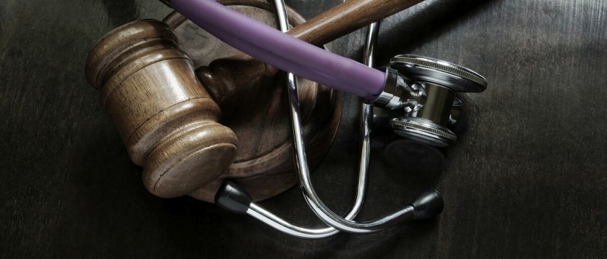 Ein Richterhammer und ein Stethoskop auf dunklem Hintergrund.