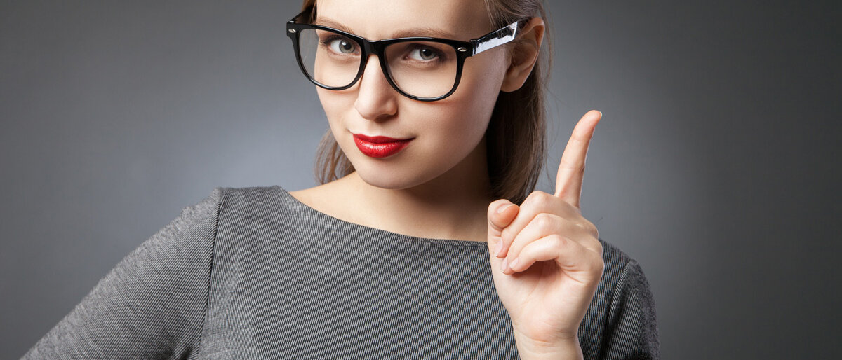 Eine junge Frau blickt streng und hebt mahnend den Zeigefinger