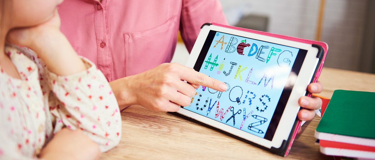 Eine Mutter erklärt ihrem Kind das Alphabet mit Hilfe eines Tablets