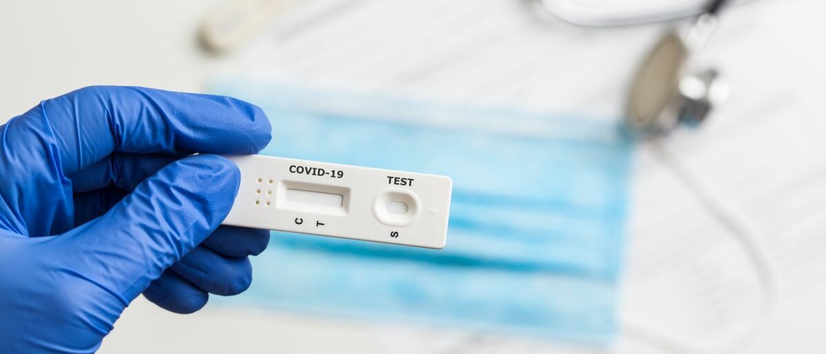 Schnelltest Eine Hand mit Einweghandschuhe hält einen Corona-Schnelltest in der Hand.