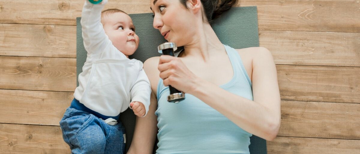 Eine Frau und ein Baby mit Hanteln liegen auf dem Rücken.