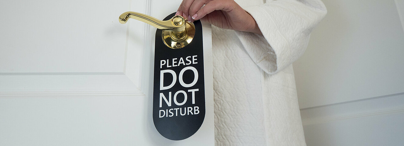 Eine Frau versieht die Tür mit einem Bitte-nicht-stören-Schild.