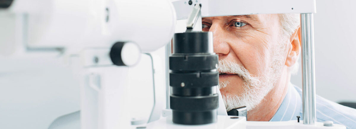 Ein Senior blickt in ein Augenmessgerät mit Licht
