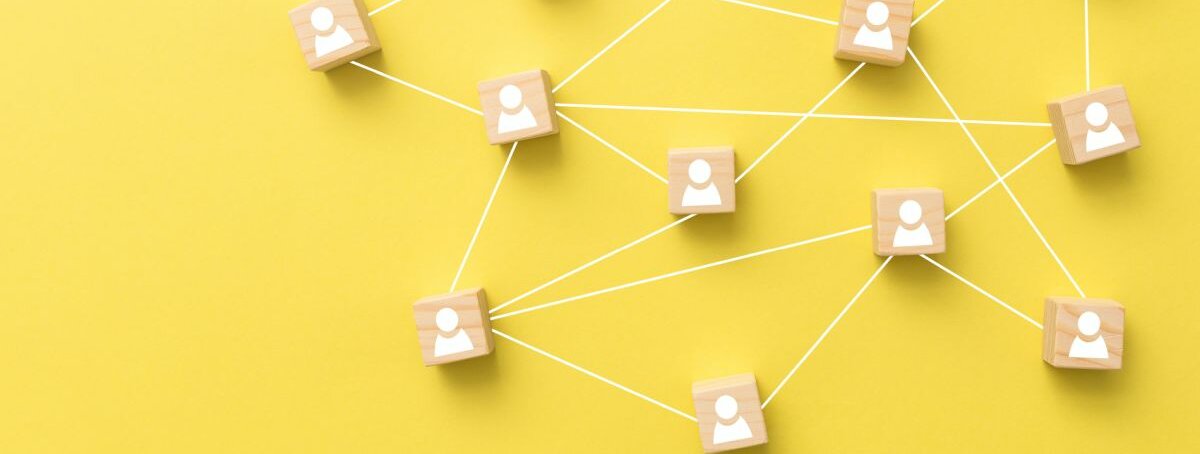 Kontakte Kleine Holzblöcke mit weißen Mensch-Symbolen auf gelbem Hintergrund.