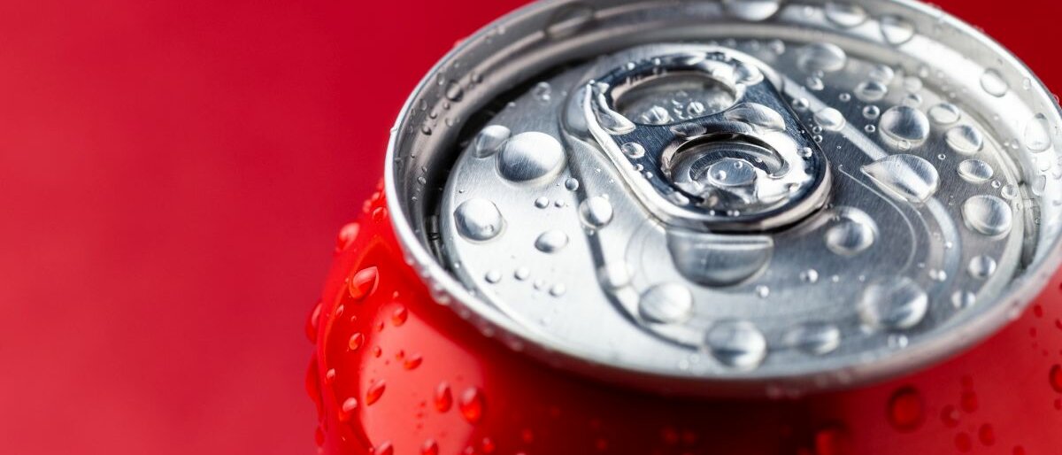 Getränkedose Eine Getränkedose mit Wassertropfen auf dem Deckel vor rotem Hintergrund.