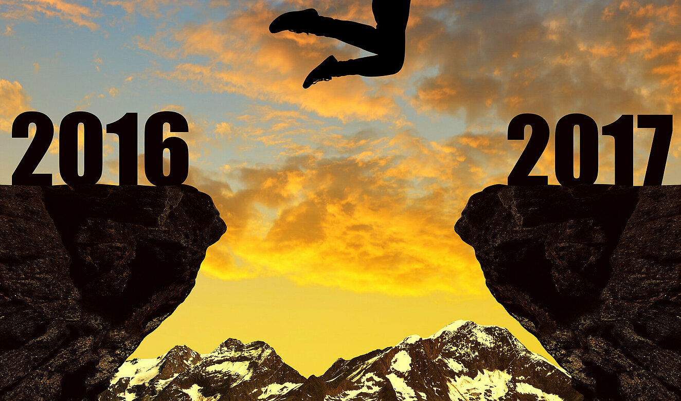 Frau springt über über eine Lücke in zwei Felsen, die das neue und das alte Jahr symbolisieren
