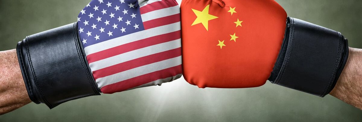 Zwei Fäuste mit Boxhandschuhen. Auf dem einen Handschuh ist die chinesische Flagge zu sehen, auf dem anderen die der USA.