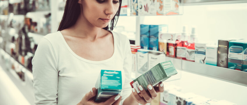 Frau steht vor Apothekenregal