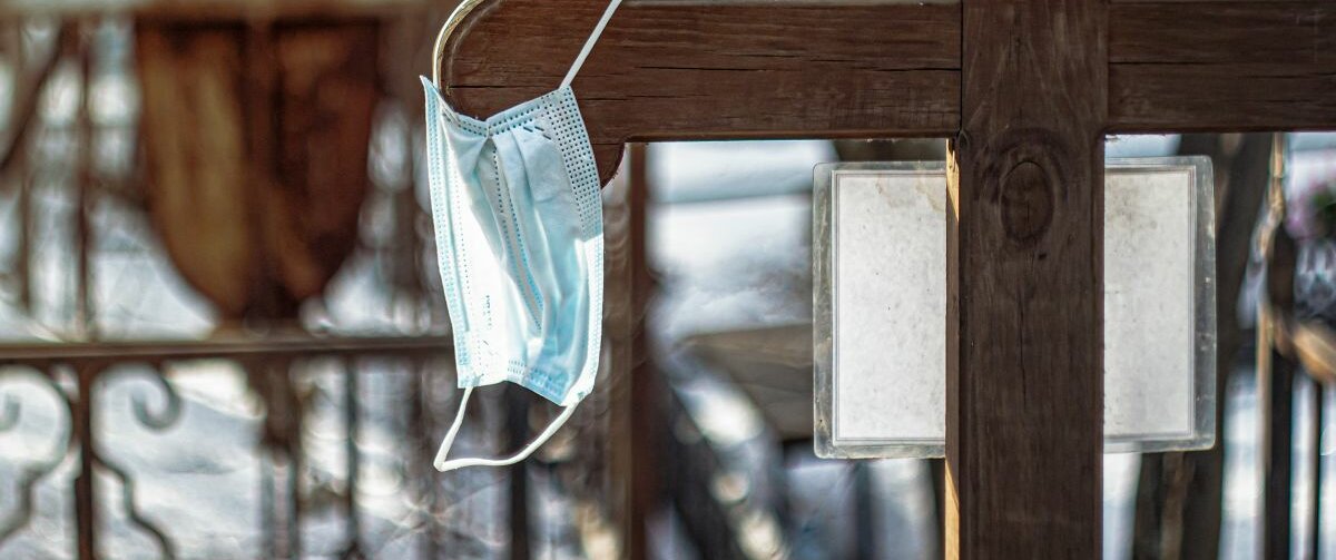 Grab Ein Holzkreuz an dem eine Maske hängt.