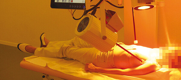 Eine Frau bekommt mit einer Infrarotlampe die Wangen bestrahlt.