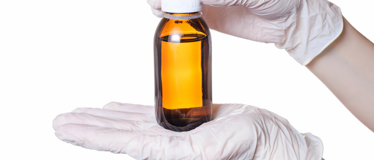 Morphin-Lösung Zwei behandschuhte Hände halten eine Braunglasflasche mit Flüssigkeit.