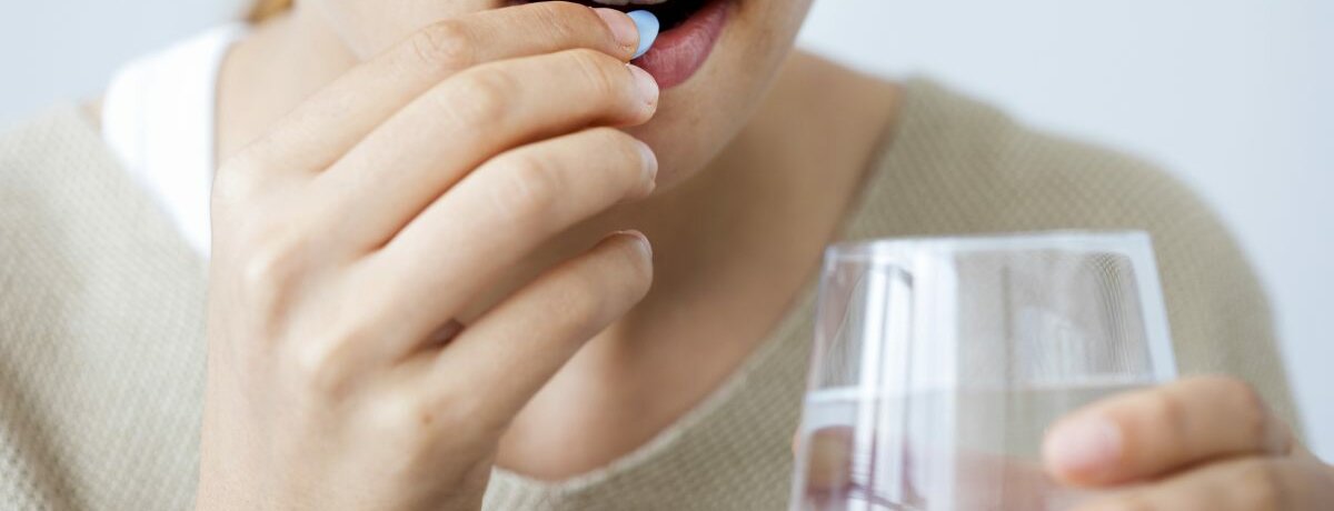 Eine Frau, die eine Tablette einnimt.