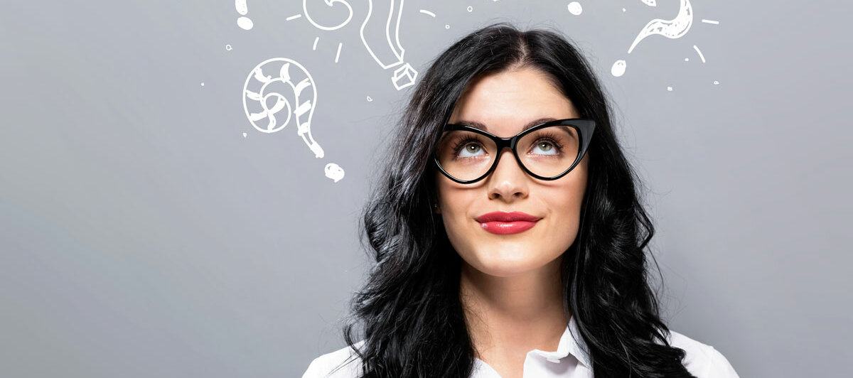 Eine Frau blickt über sich, dort sind viele Fragezeichen eingezeichnet.