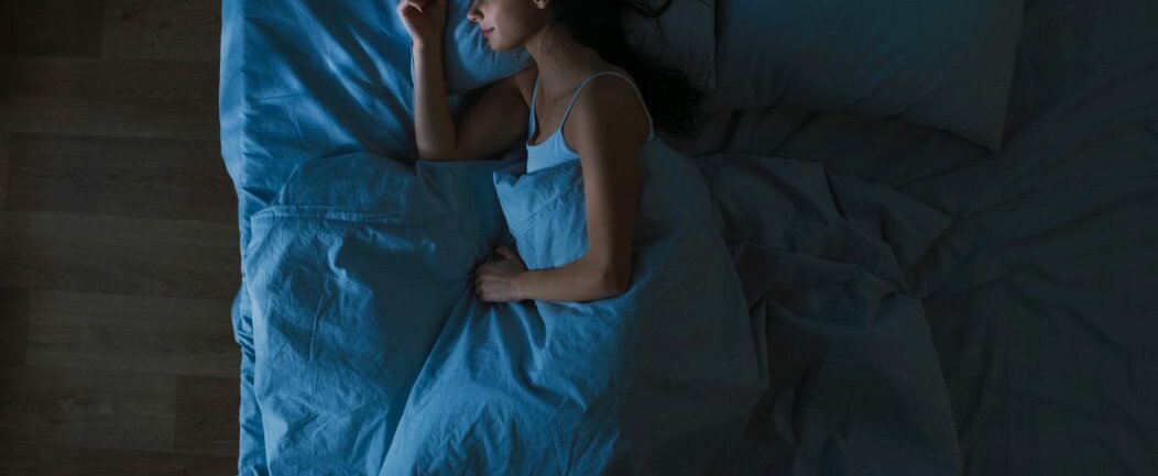 Eine Frau schläft im Bett und es ist dunkel.