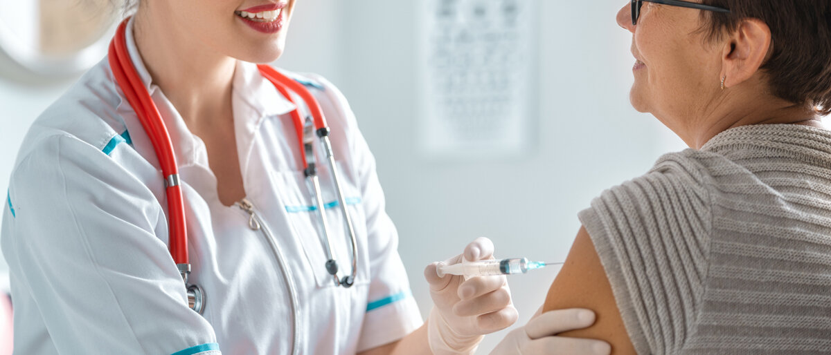 Eine Ärztin impft eine Frau in den Oberarm.