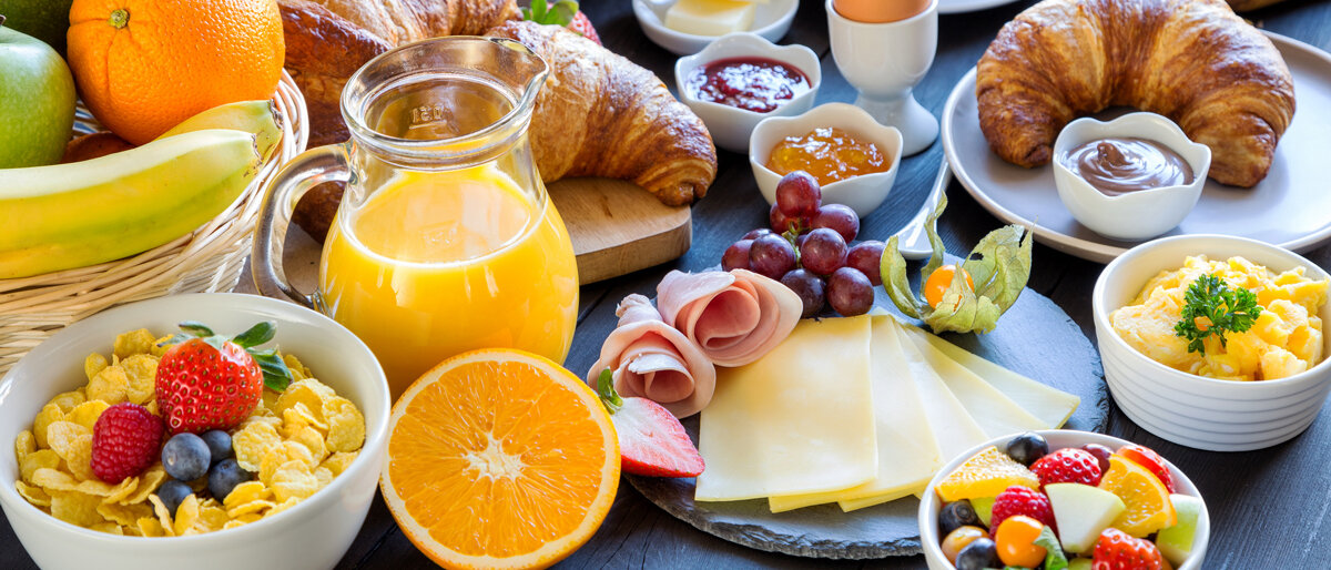 Auf dem Frühstückstisch stehen zahlreiche verschiedene Speisen.