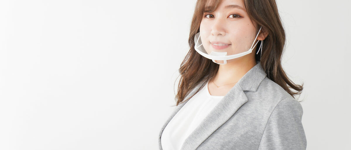 Eine Frau trägt eine Kunststoffmaske über Mund und Nase.
