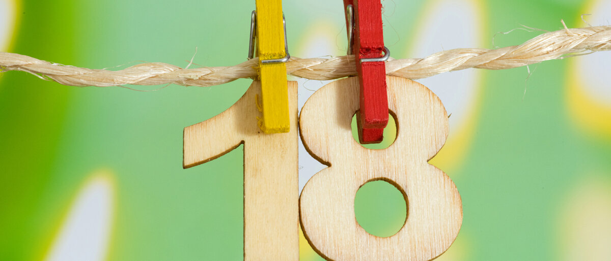 Die Zahl 18 aus Holz hängt an einer Leine.