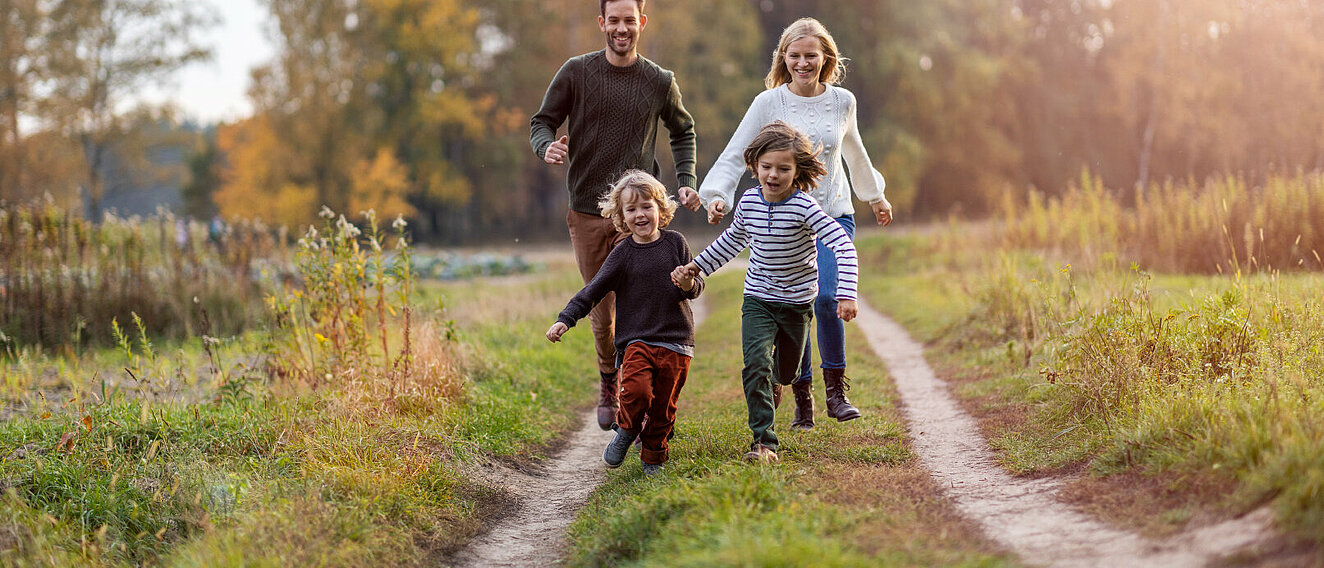 Familie läuft auf Waldweg. © PIKSEL / iStock / Getty Images Plus