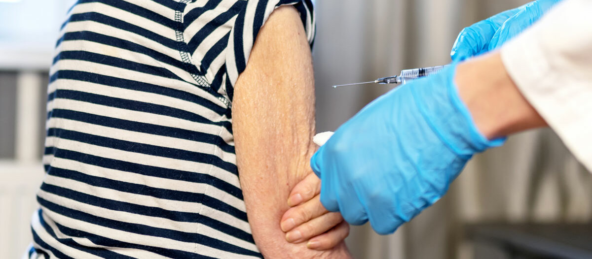 Eine Seniorin erhält eine Spritze in den Oberarm.