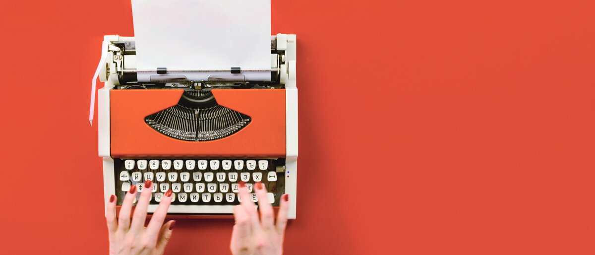 Eine Schreibmaschine, auf der rot lackierte Hände tippen
