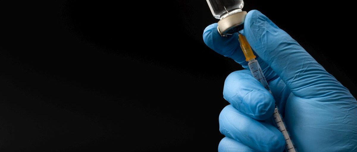 Impfstoff Hände tragen blaue chirurgische Latexhandschuhe füllen eine Spritze.