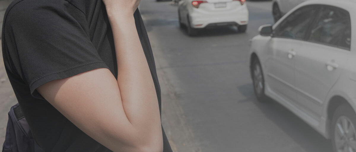Smog Eine Frau steht an stark befahrener Straße und schützt Nase und Mund vor dem Smog