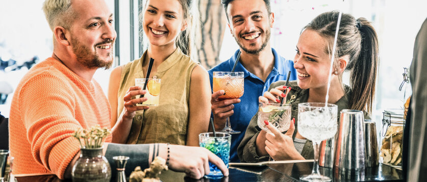 Personen trinken Coktails an einer Bar. © ViewApart / iStock / Getty Images