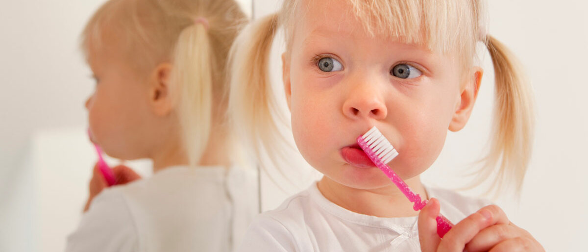 Mädchen mit blonden Zöpfen putzt Zähne