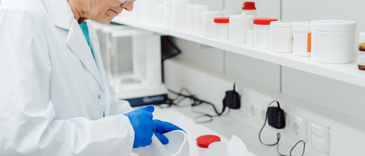 Eine Frau im weißen Kittel rührt eine Rezeptur in der Apotheke zusammen