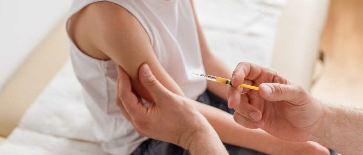 Ein kleines Kind erhält eine Impfung in den Oberarm.