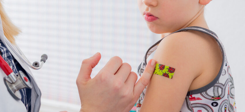 Kind bekommt Pflaster auf den Arm