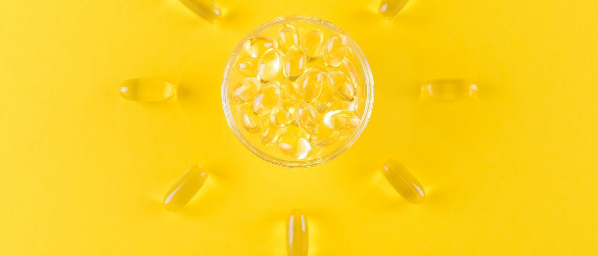 Omega3-Kapseln Omega3-Kapseln, die wie eine Sonne angeordnet auf einem gelben Untergrund liegen.